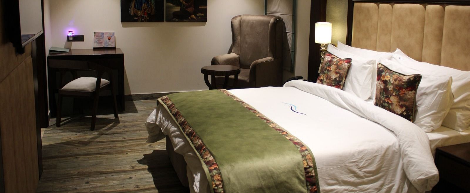 Side view of a bedroom featuring a working table, a chair, and portraits adorning the wall at BluSalzz Residence, Amritsar
